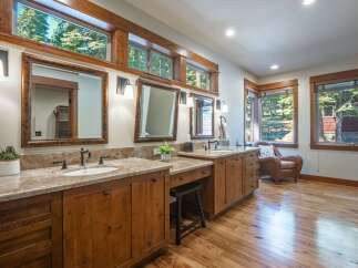 This spacious bathroom features dual vanities with granite countertops and ample wooden cabinetry, perfect for storage.