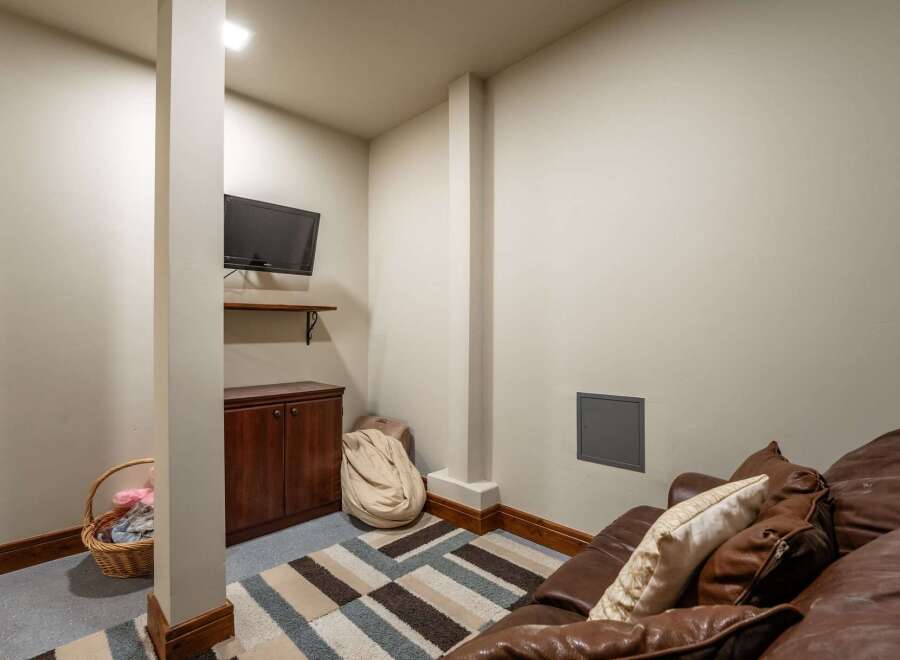 This cozy basement living area features a comfortable brown leather sofa with decorative pillows, perfect for relaxing or entertaining.