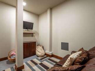 This cozy basement living area features a comfortable brown leather sofa with decorative pillows, perfect for relaxing or entertaining.