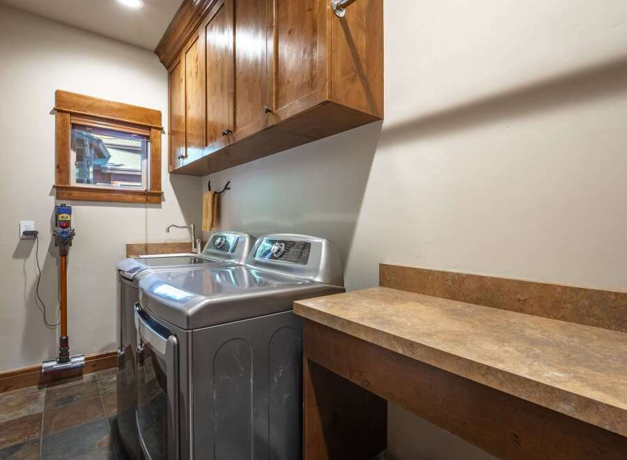This laundry room boasts a sleek, modern aesthetic with stainless steel appliances, including a top-load washer and dryer.