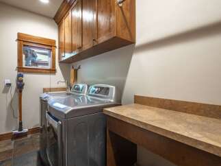 This laundry room boasts a sleek, modern aesthetic with stainless steel appliances, including a top-load washer and dryer.