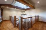 Ascend to the upper level via a beautifully crafted wooden staircase, bathed in natural light from a striking skylight.
