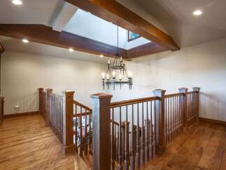 Ascend to the upper level via a beautifully crafted wooden staircase, bathed in natural light from a striking skylight.