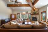 Experience rustic charm in this spacious living room, featuring a grand stone fireplace and exposed wooden beams that add warmth and character.