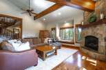 Experience rustic elegance in this spacious living room, featuring a grand stone fireplace and exposed wooden beams that create a warm, inviting atmosphere.