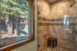 Experience luxury in this stunning bathroom featuring a spacious walk-in shower with elegant marble tile and a built-in wooden bench.