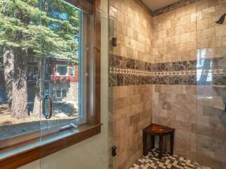 Experience luxury in this stunning bathroom featuring a spacious walk-in shower with elegant marble tile and a built-in wooden bench.