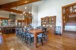 Experience rustic elegance in this spacious dining area, featuring a grand wooden dining table with seating for ten, illuminated by a striking chandelier.