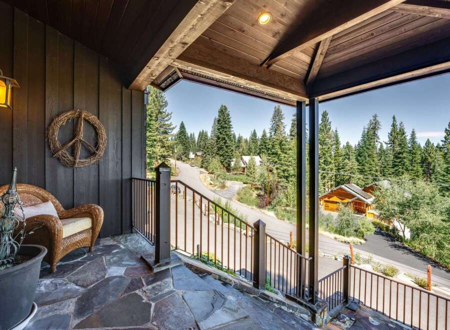 Experience serene mountain living from this charming porch, offering a peaceful retreat amidst towering pine trees.