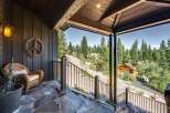 Experience serene mountain living from this charming porch, offering a peaceful retreat amidst towering pine trees.