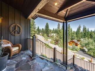 Experience serene mountain living from this charming porch, offering a peaceful retreat amidst towering pine trees.