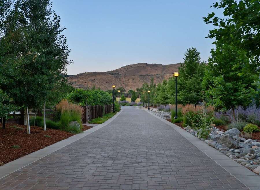Discover an exquisite property featuring a beautifully paved driveway lined with mature trees and vibrant landscaping.