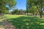 Discover this expansive green lawn, perfect for outdoor activities and gatherings, framed by mature trees offering ample shade.
