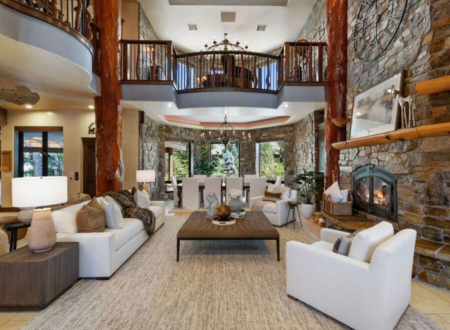 Experience luxurious mountain living in this grand lodge-style great room, featuring a soaring stone fireplace and exposed wooden beams.