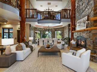 Experience luxurious mountain living in this grand lodge-style great room, featuring a soaring stone fireplace and exposed wooden beams.