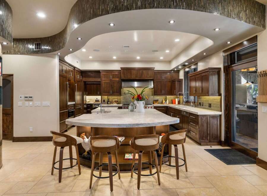 Experience luxury in this expansive gourmet kitchen, featuring rich custom cabinetry and a stunning waterfall island perfect for entertaining.