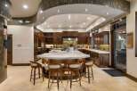 Experience luxury in this expansive gourmet kitchen, featuring rich custom cabinetry and a stunning waterfall island perfect for entertaining.
