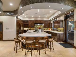 Experience luxury in this expansive gourmet kitchen, featuring rich custom cabinetry and a stunning waterfall island perfect for entertaining.
