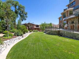 This stunning backyard offers a lush green lawn perfect for recreation and relaxation, bordered by a charming rock garden and mature trees.