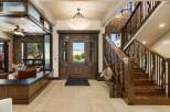 Step into luxury with this grand entryway featuring a stunning double wooden door with glass inlays, offering a picturesque view of the surrounding landscape.