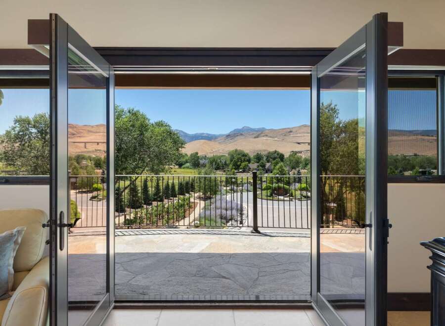 Experience breathtaking panoramic views from this stunning property, featuring expansive glass doors that open to a picturesque landscape.