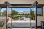 Experience breathtaking panoramic views from this stunning property, featuring expansive glass doors that open to a picturesque landscape.