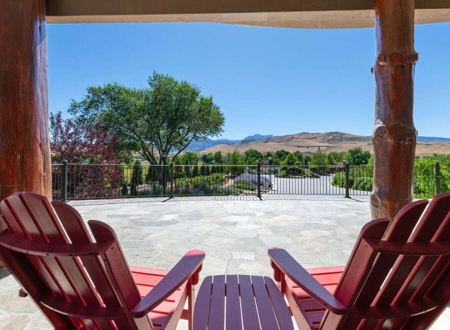 Enjoy breathtaking mountain views from this stunning property's expansive patio, complete with comfortable Adirondack chairs and a charming side table.
