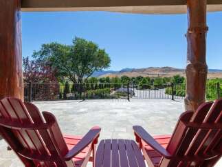 Enjoy breathtaking mountain views from this stunning property's expansive patio, complete with comfortable Adirondack chairs and a charming side table.