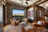 Experience breathtaking mountain views from this luxurious living room, featuring a stunning stone accent wall and a large picture window.