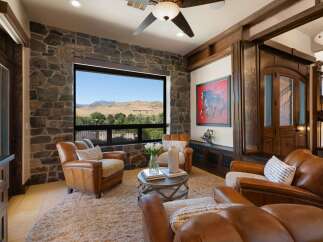 Experience breathtaking mountain views from this luxurious living room, featuring a stunning stone accent wall and a large picture window.