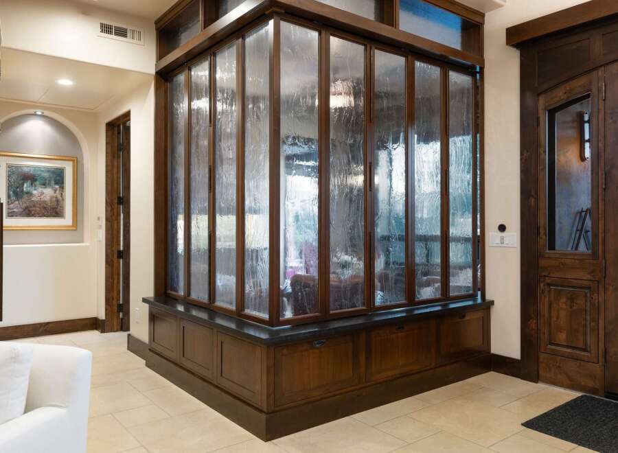 Step into this grand entryway featuring a stunning textured glass partition with rich wood framing, creating a unique visual element.