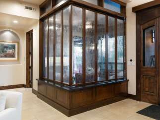 Step into this grand entryway featuring a stunning textured glass partition with rich wood framing, creating a unique visual element.