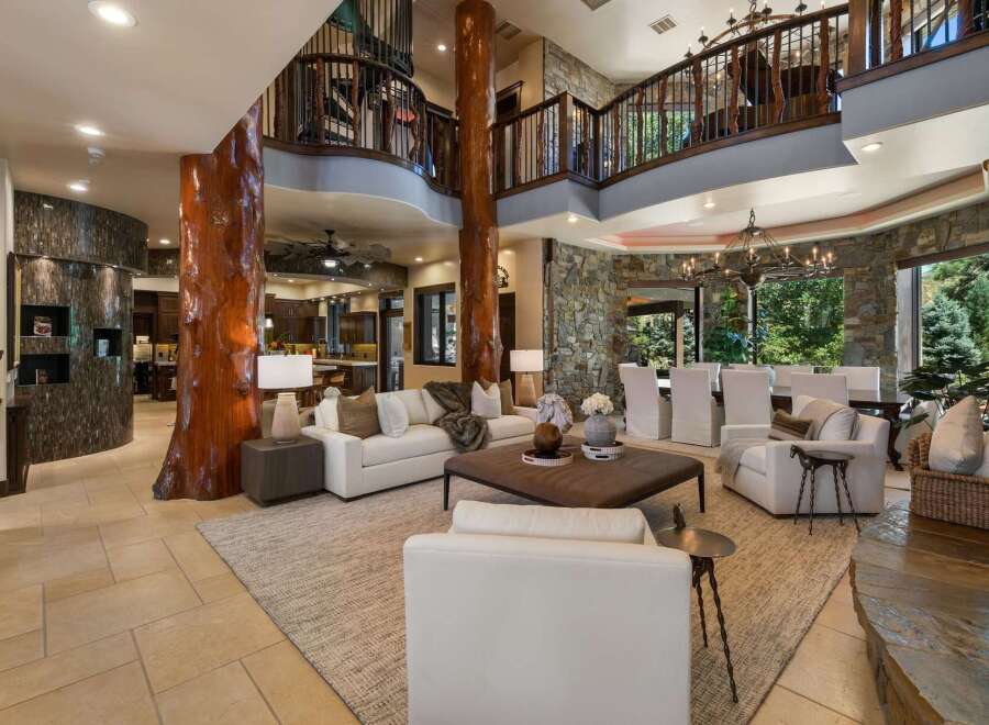 Experience luxury living in this grand great room, featuring a stunning natural wood pillar and a soaring two-story balcony.