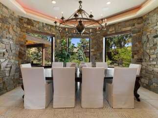 Experience elegant dining in this stunning room featuring a grand chandelier and floor-to-ceiling stone walls.