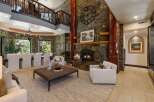 Experience rustic elegance in this grand living space, featuring a towering stone fireplace with a prominent clock and natural wood accents.