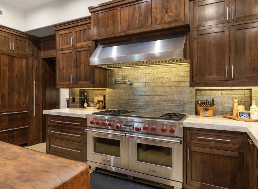 Experience luxury in this gourmet kitchen, featuring a professional-grade Wolf range with double ovens and a pot filler, complemented by custom dark wood cabinetry.
