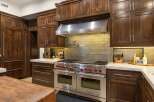Experience luxury in this gourmet kitchen, featuring a professional-grade Wolf range with double ovens and a pot filler, complemented by custom dark wood cabinetry.