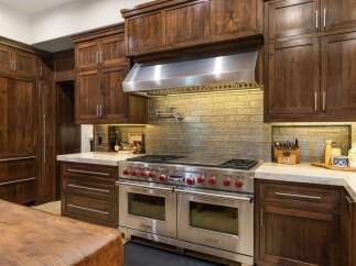 Experience luxury in this gourmet kitchen, featuring a professional-grade Wolf range with double ovens and a pot filler, complemented by custom dark wood cabinetry.