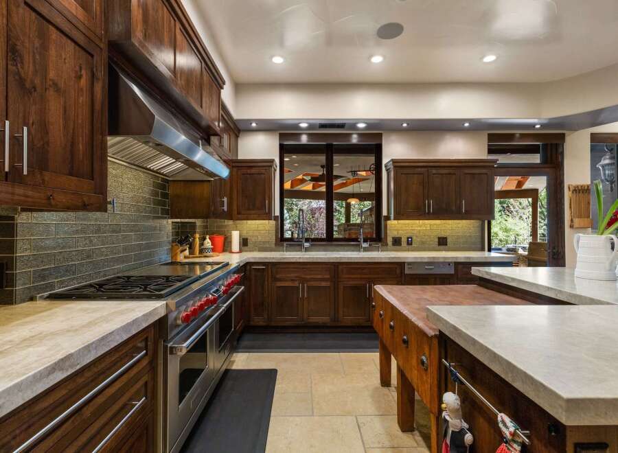 Experience luxury in this gourmet kitchen, featuring rich walnut cabinetry and a professional-grade stainless steel range with striking red knobs.