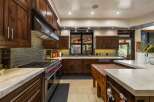 Experience luxury in this gourmet kitchen, featuring rich walnut cabinetry and a professional-grade stainless steel range with striking red knobs.