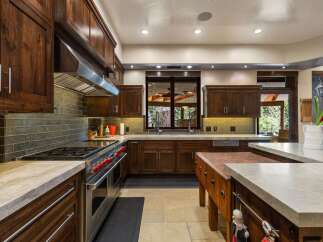 Experience luxury in this gourmet kitchen, featuring rich walnut cabinetry and a professional-grade stainless steel range with striking red knobs.