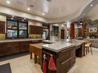 Experience luxury living in this stunning kitchen featuring rich dark wood cabinetry and expansive marble countertops.