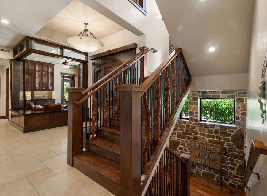 Experience luxury living with this stunning staircase, featuring rich wooden treads and intricate metal balusters that add a touch of rustic elegance.