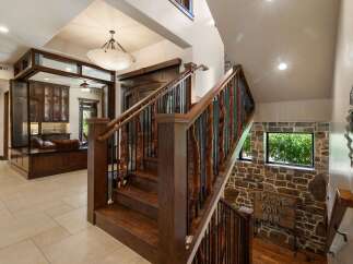 Experience luxury living with this stunning staircase, featuring rich wooden treads and intricate metal balusters that add a touch of rustic elegance.