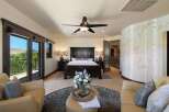 Experience luxury in this master suite featuring a grand dark wood bed and matching nightstands, complemented by a cozy seating area with plush leather chairs.