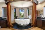 Indulge in luxury in this stunning bathroom featuring a unique stone bathtub adorned with a plush white fur throw.