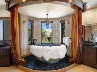 Indulge in luxury in this stunning bathroom featuring a unique stone bathtub adorned with a plush white fur throw.