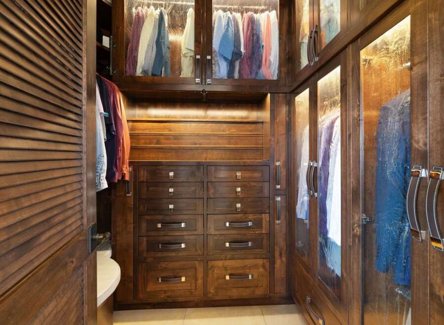 Step into this luxurious walk-in closet, featuring rich dark wood cabinetry and ample storage solutions.