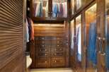 Step into this luxurious walk-in closet, featuring rich dark wood cabinetry and ample storage solutions.