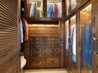 Step into this luxurious walk-in closet, featuring rich dark wood cabinetry and ample storage solutions.